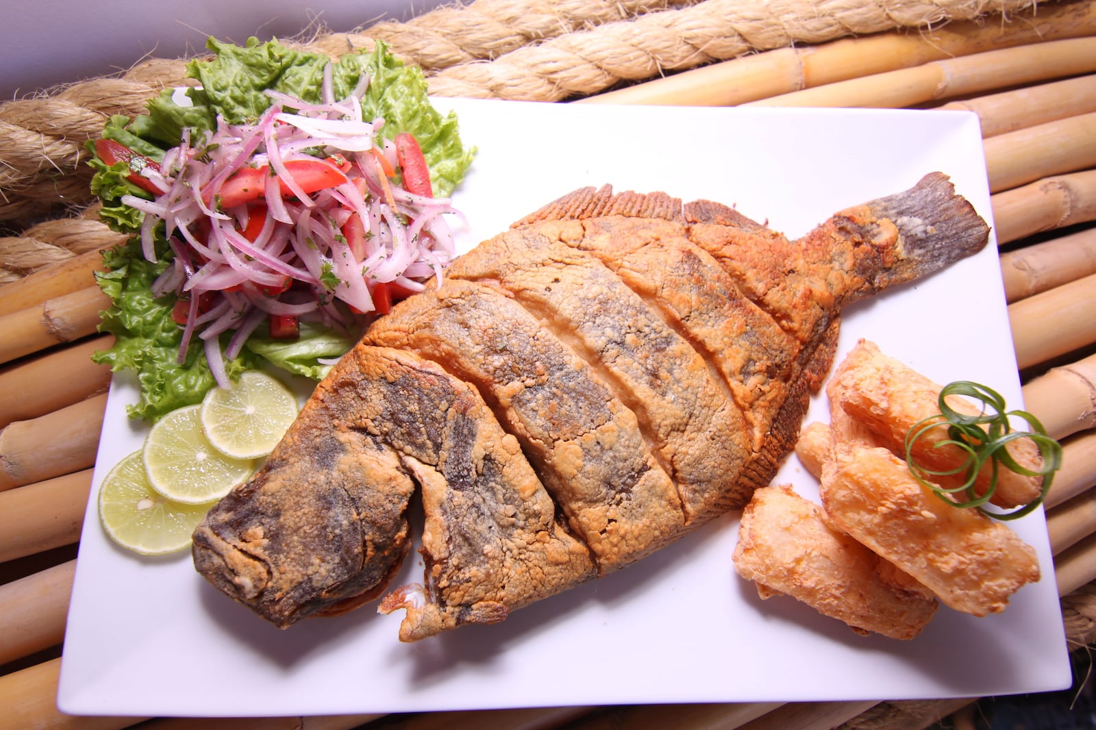 Peixe frito peruano deliciosamente preparado, servido com salada fresca, fatias de limão e mandioca crocante Paolo Diaz
